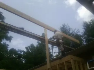 Carpenter setting a ridge beam over a new addition frame — Ice Dam Removal by Roofing Brothers in Hesston