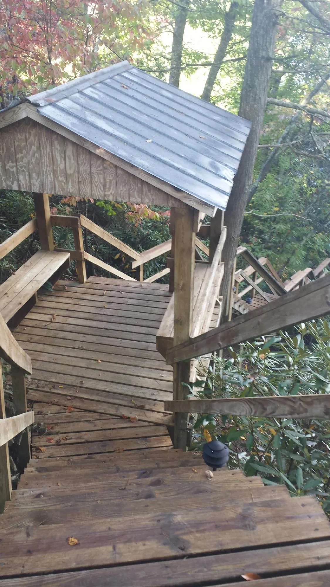 Metal roofed shelter over wooden steps on a wooded walkway — Skylight Repair & Installation work by our crew in Hesston